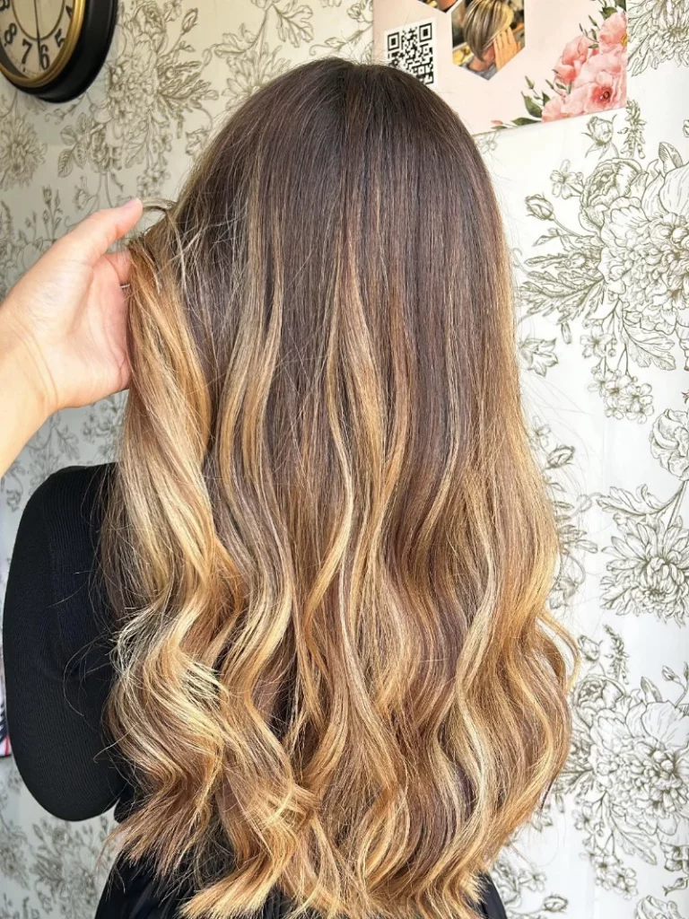 Client aux cheveux longs avec coloration et mèches, coiffage wavy réalisé en salon par Mademoiselle S Coiffeuse Visagiste, pour un résultat naturel et lumineux.